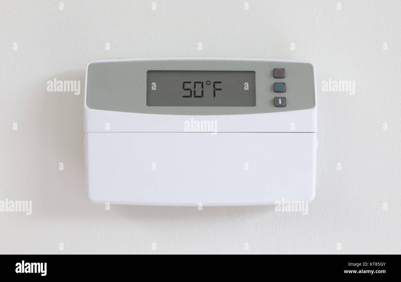 Vintage digital thermostat hanging on a white wall - Covert in dust - 50 degrees fahrenheid Stock Photo
