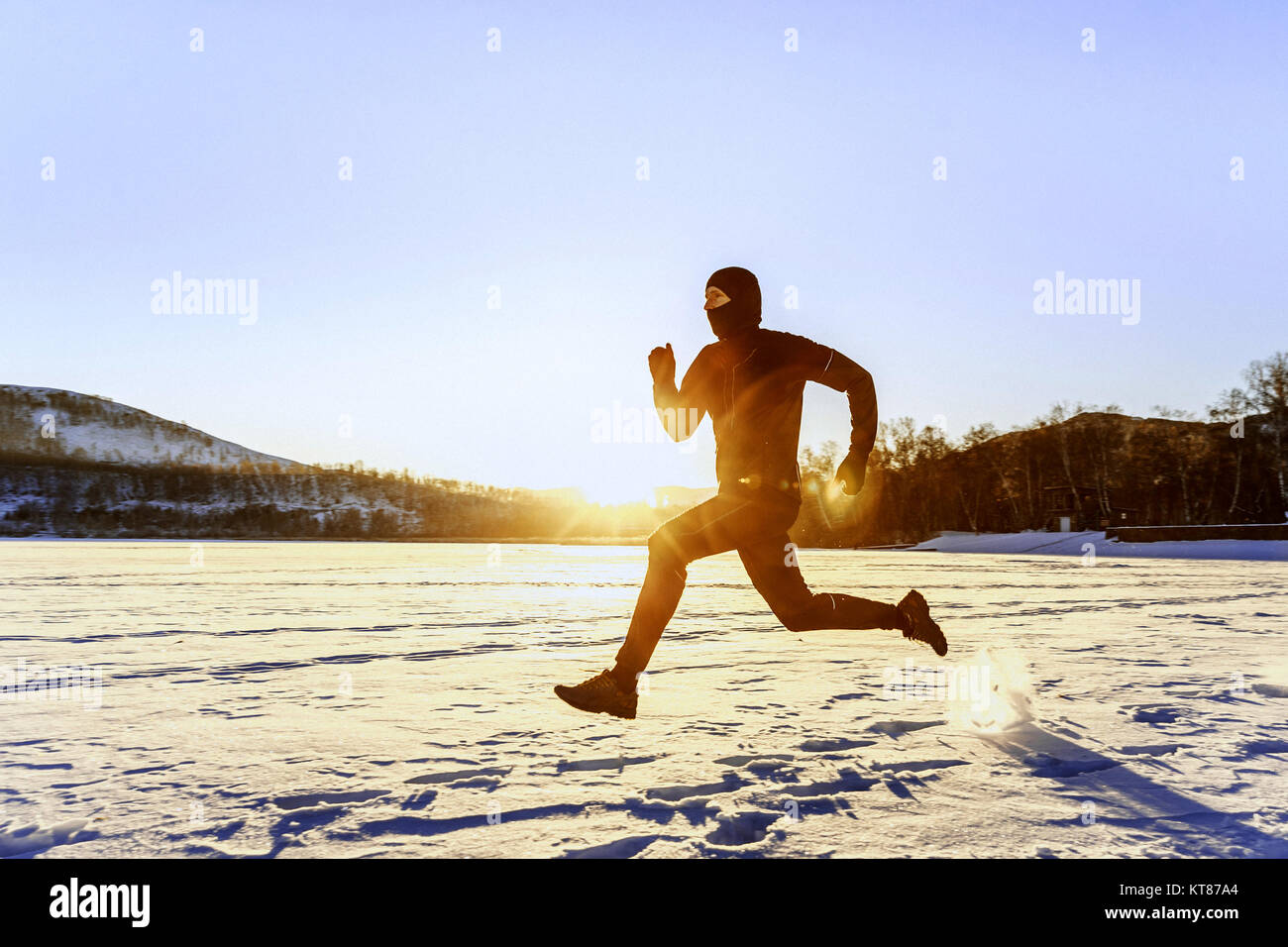 morning winter running athlete runner in rays of sunrise Stock Photo