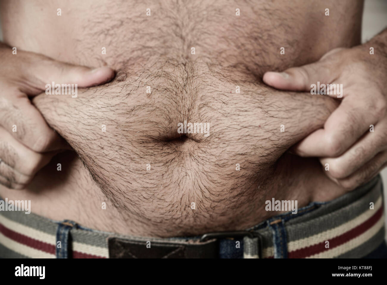 closeup of a young caucasian man grabbing the fat of his hairy stomach Stoc...