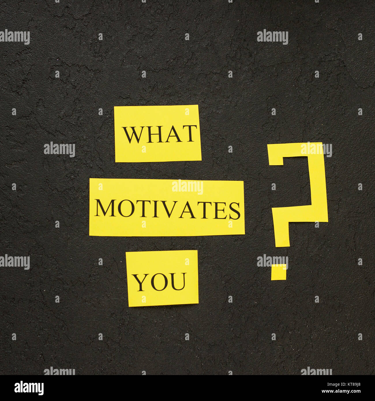 What motivates you question printed on a yellow paper. Black concrete background. Business and work concept. Space for your text or product display.To Stock Photo