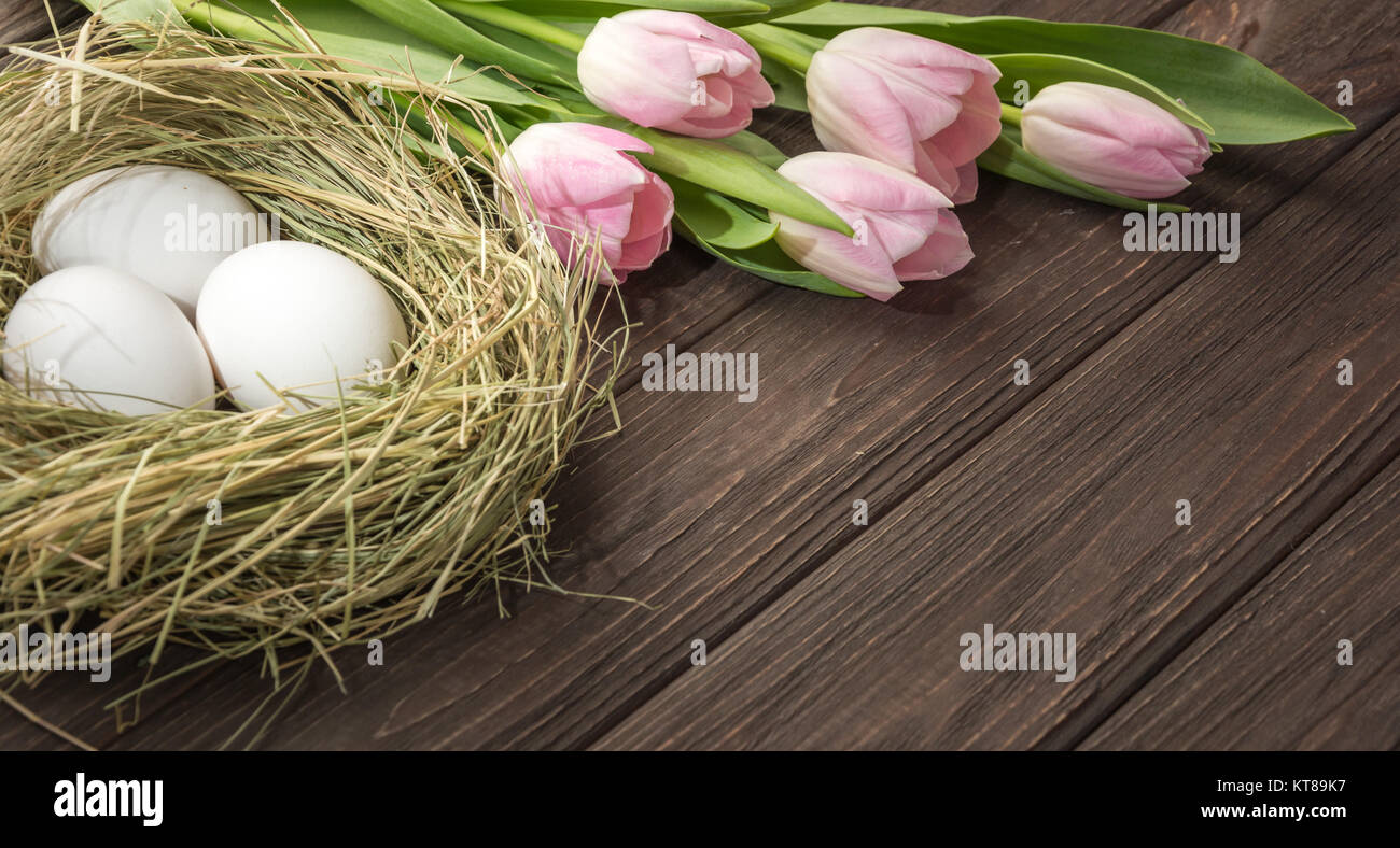 Easter eggs in a straw nest and tulips Stock Photo - Alamy