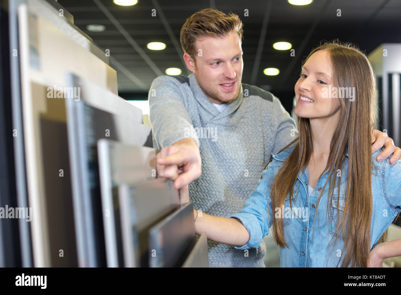 young happy couple looking at bathroom tile in furniture store Stock Photo
