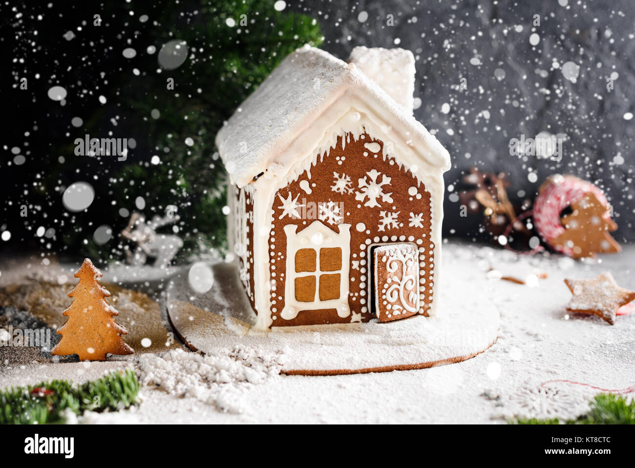 Homemade gingerbread house, falling snow and festive Christmas decorations. Christmas card, winter still life. Copy space for text Stock Photo