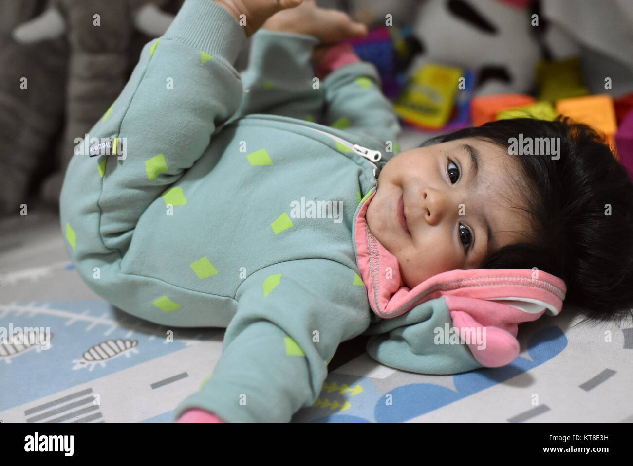 Playful happy baby girl smiles holding her legs up Stock Photo