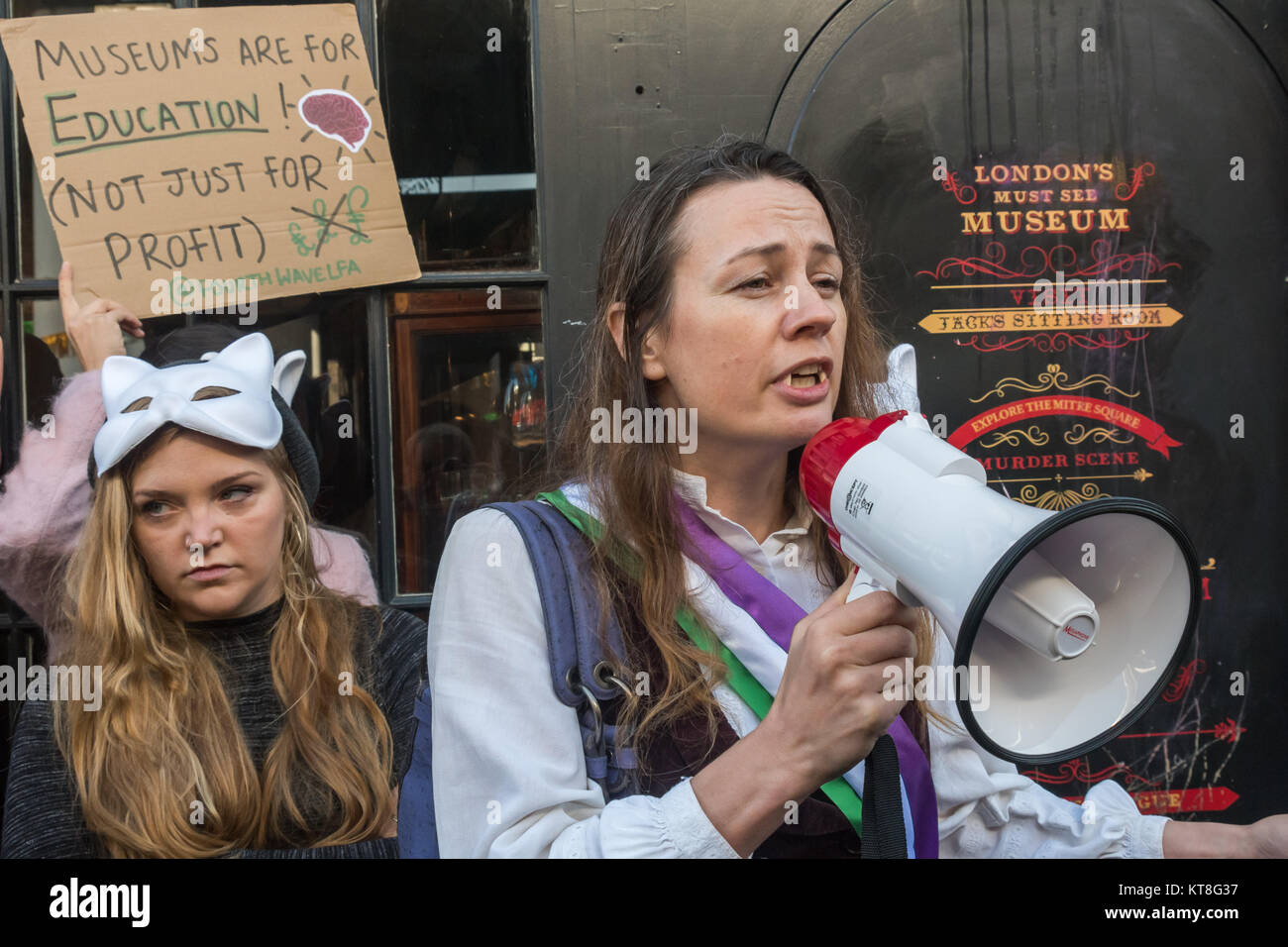 A woman with 'Dracula' fangs and a Suffragette sash speaks at the Fourth Wave LFA protest at Ripper 'museum' in Cable St after macabre and highly misogynist Halloween publicity. Stock Photo
