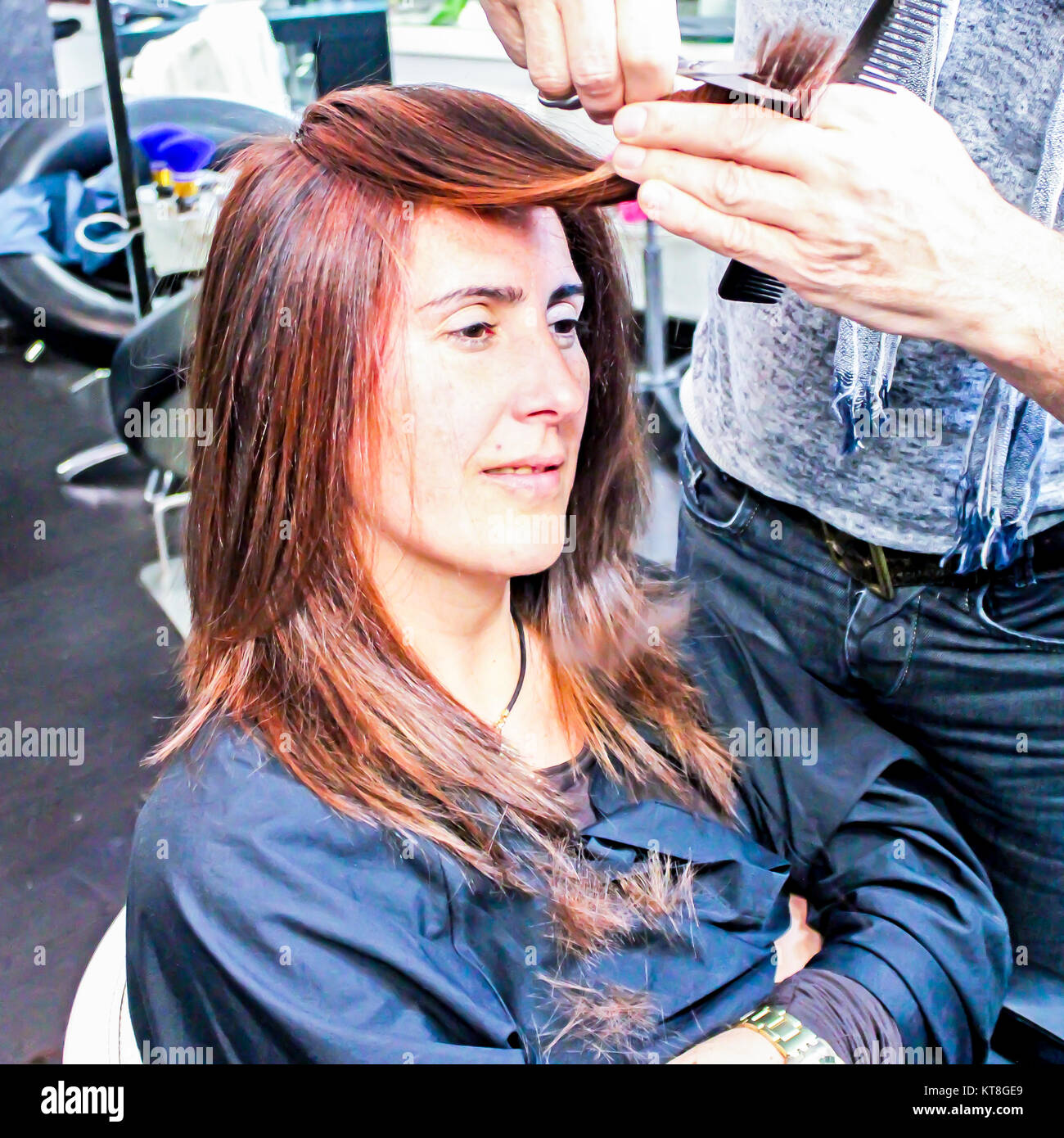 Woman Having Her Long Red Hair Cut By A Stylist Man With