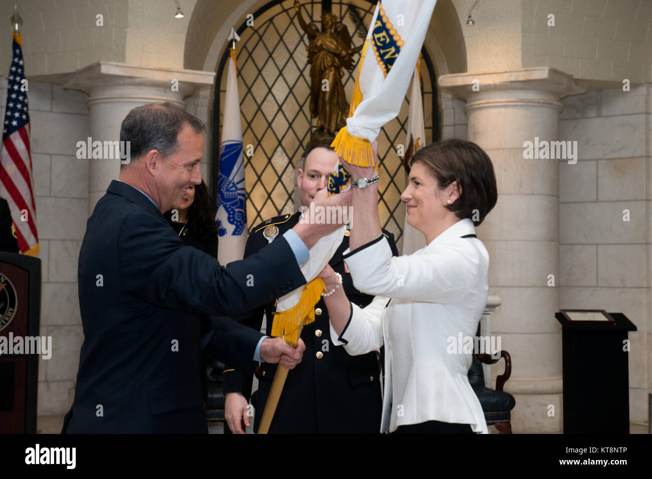 Gerald B. O’Keefe, left, administrative assistant to the Secretary of the Army, hands a Senior Executive Service flag to Katharine Kelley, superintendent, Arlington National Cemetery, during her SES induction ceremony, March 2, 2017, in Arlington, Va. The ceremony took place in the lower level of the Memorial Amphitheater in the cemetery. (U.S. Army photo by Rachel Larue/Arlington National Cemetery/released) Stock Photo