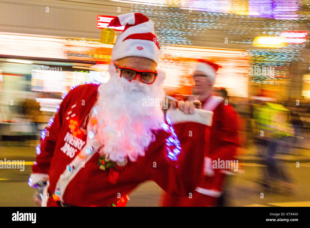 London, UK. 23rd Dec, 2017. A horde of rollerblading Santas skate down Oxford Street as shoppers crowd London on the second last shopping days before Christmas. Credit: Paul Davey/Alamy Live News Stock Photo