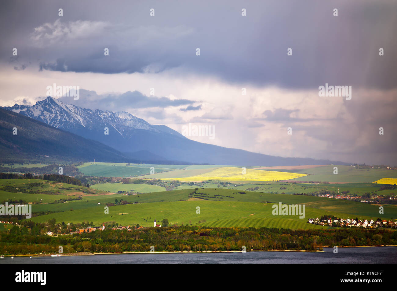 Town on the lake behind the foothills. Spring rain and storm in mountains Stock Photo