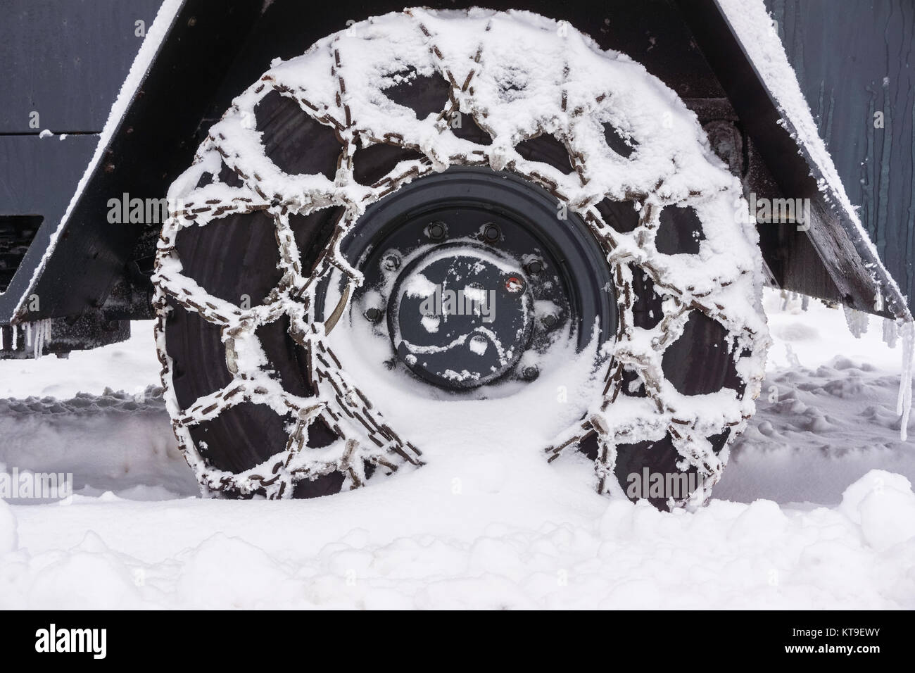 Close-up of a snowy chained wheel of a snow plow in winter Stock Photo