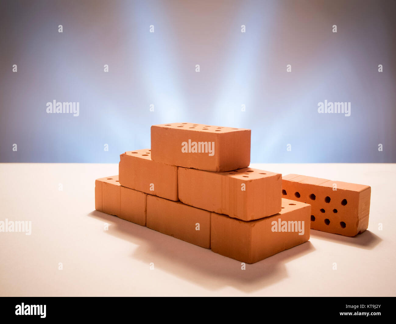 Gestapelte Modell-Ziegelsteine auf weißen Untergrund mit sternförmig beleuchteten Hintergrund. Stock Photo