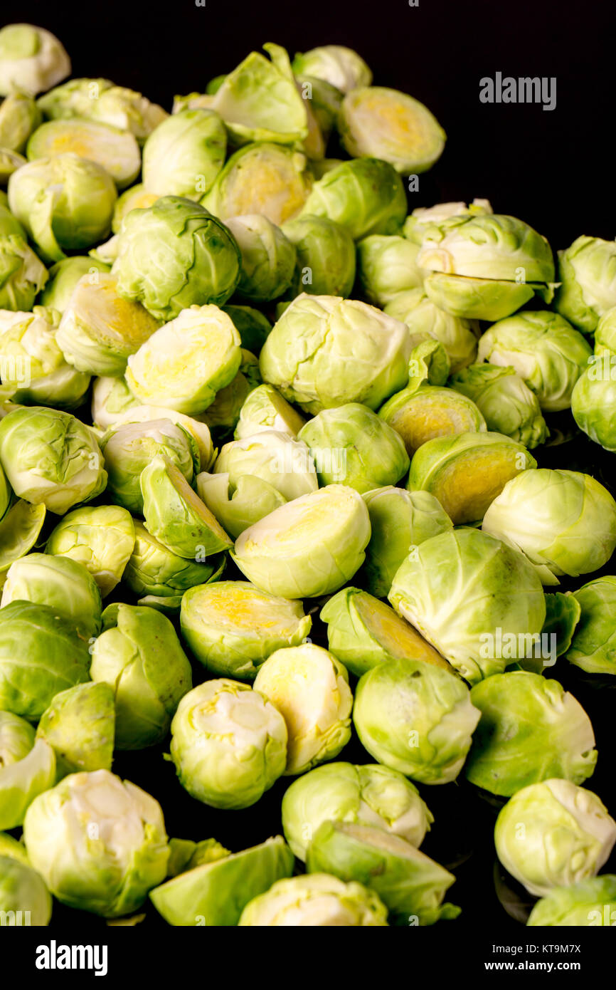 green fresh whole and cut organic Brussels sprouts, isolated on black