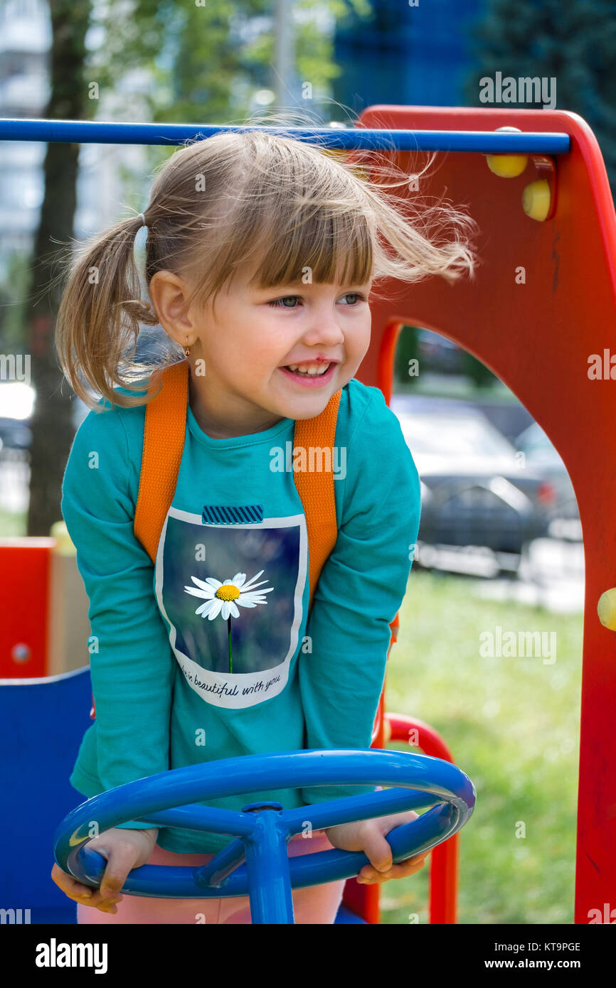 Portrait of a little girl driving a car on a playground Stock Photo