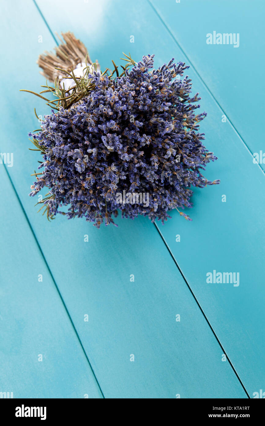 a bunch of lavender is hanging on a mediterranean-blue wooden wall to dry Stock Photo