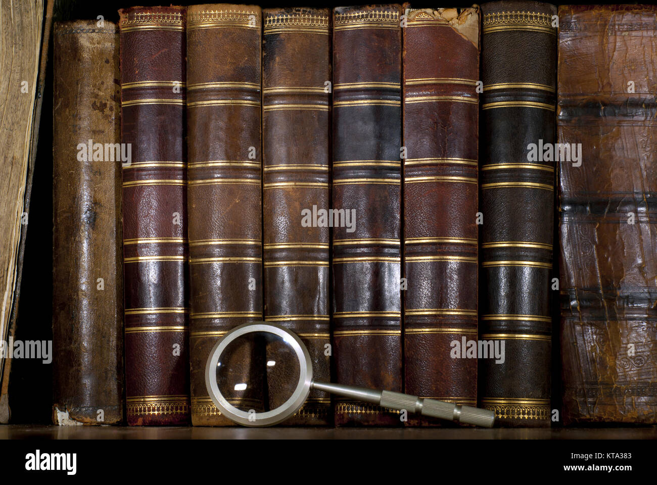 background a row of worn leather antiquarian book spines with gold