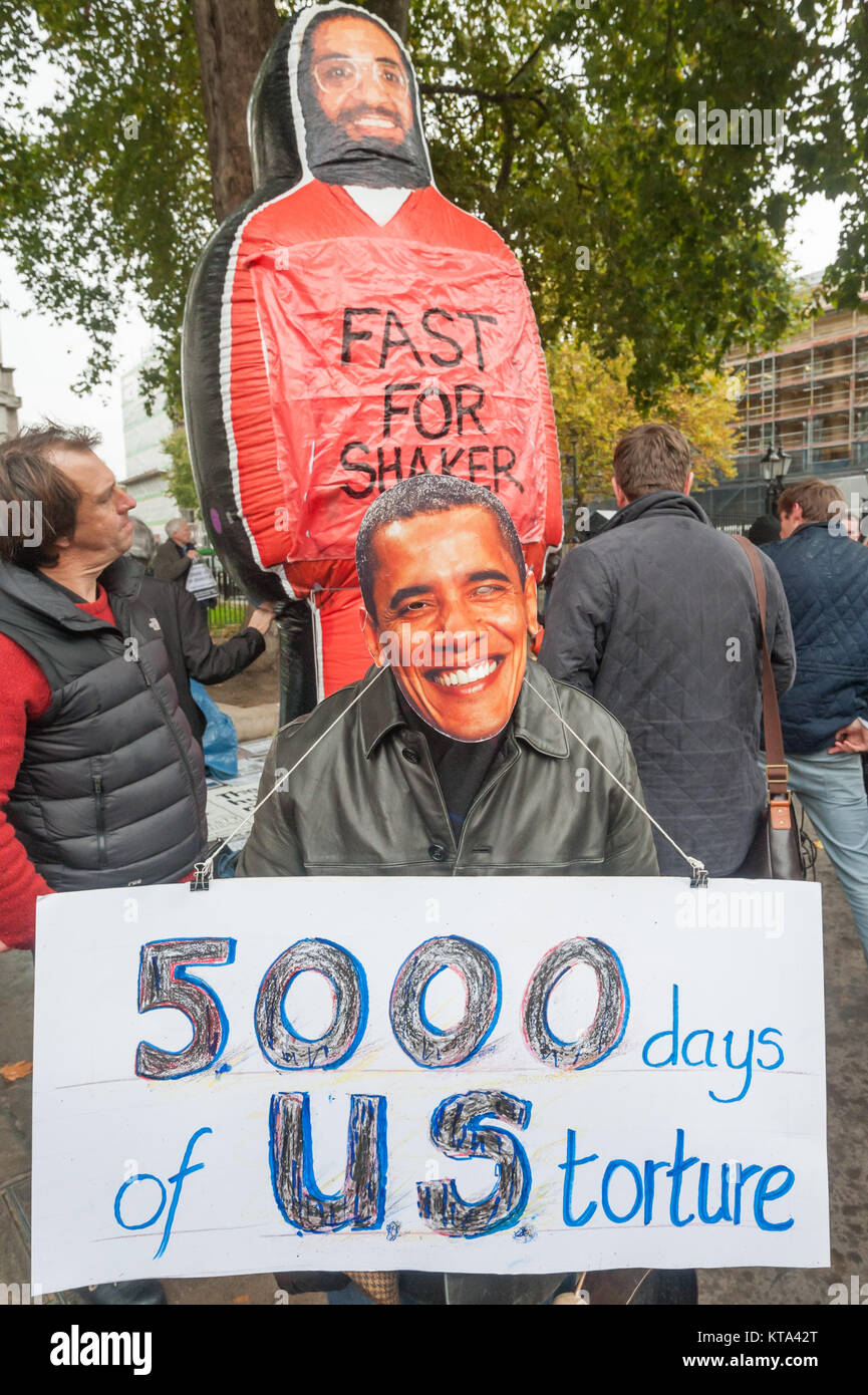 A man wears an Obama mask and has a poster '5000 days of US Torture ...