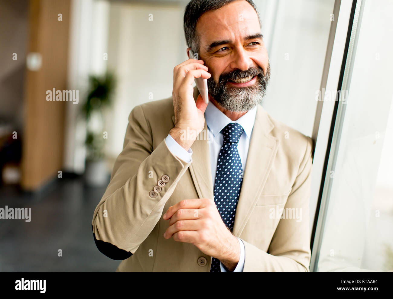 Handsome mature businessman with mobile phone in the office Stock Photo ...