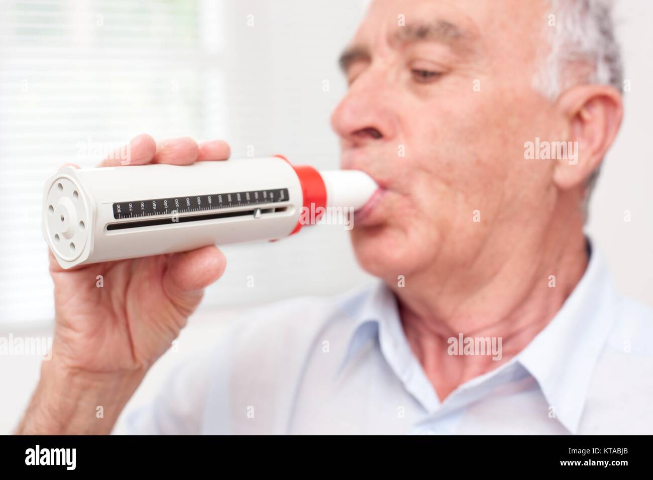 Senior man exhaling into a peakflow reader. Stock Photo