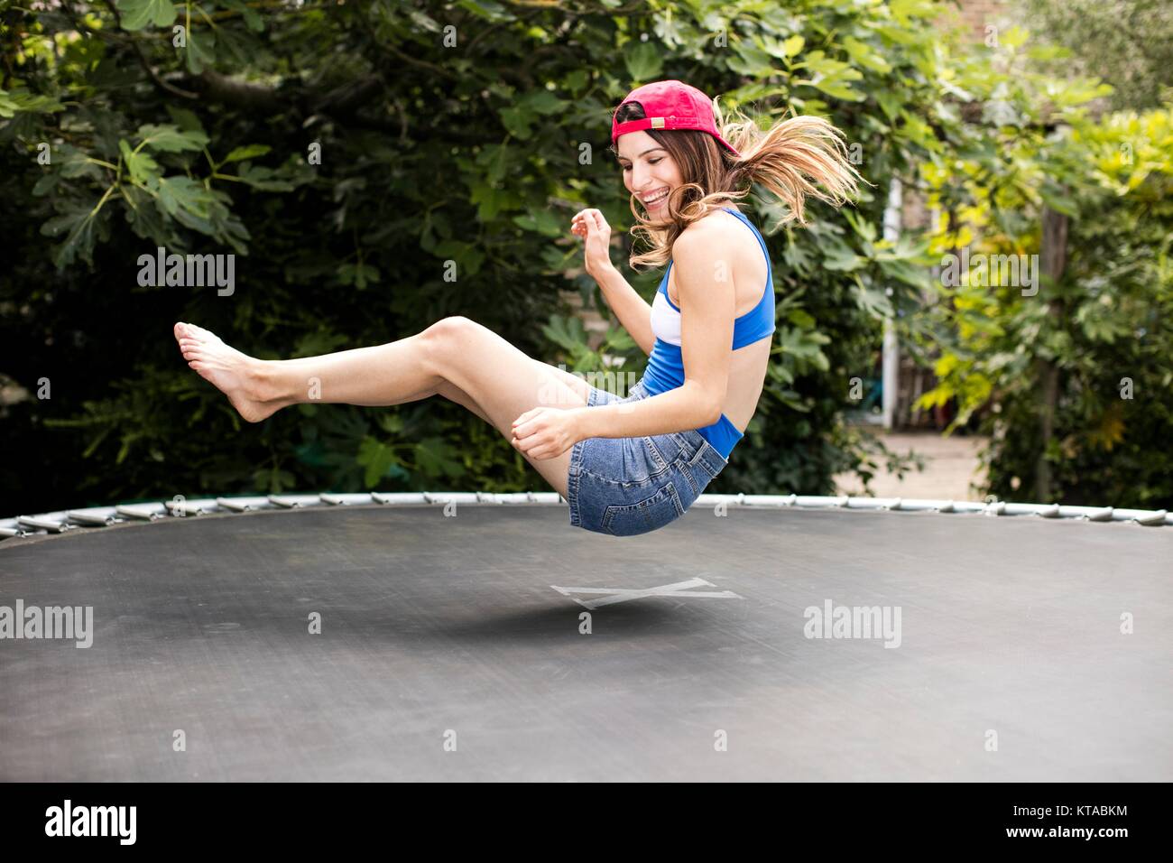 Young woman bouncing on trampoline. Stock Photo