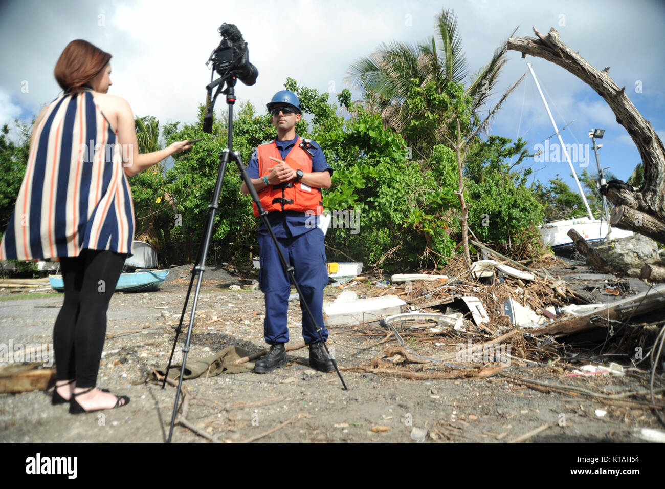 Coast Guard Petty Officer 1st Class Mark Molina, with the Hurricane Maria ESF-10 Puerto Rico response, is interviewed by reporter Heidee Rolón with El Nuevo Día, as salvage crews working with ESF-10 use a crane barge to remove a wrecked vessel in Sardinera, Puerto Rico, Dec. 21, 2017. The ESF-10 is offering no-cost options for removing vessels damaged by Hurricane Maria; affected boat owners are asked to call the Vessel Owner Outreach Hotline at (786) 521-3900. (U.S. Coast Guard Stock Photo
