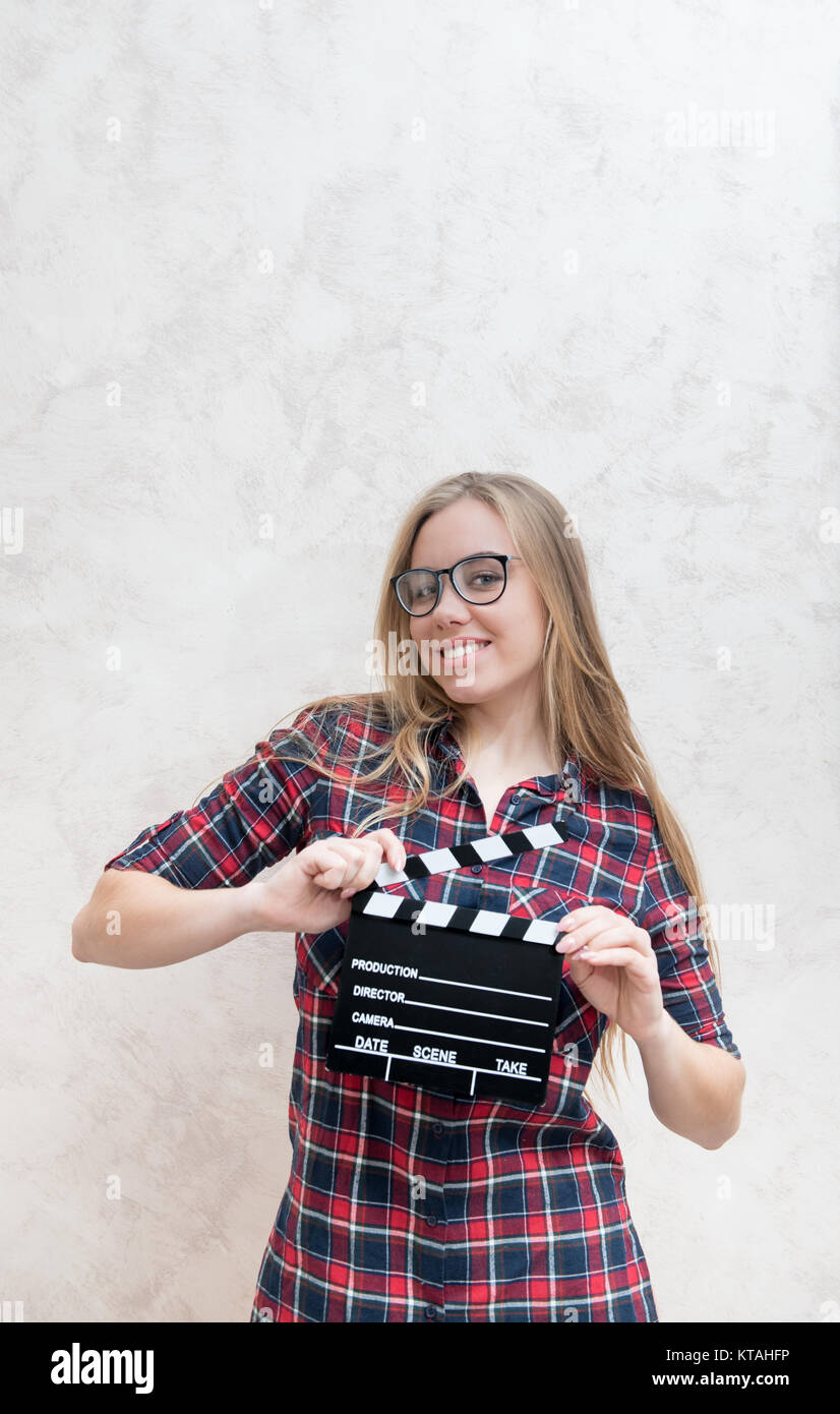 Young blonde woman actress posing with movie clapper board smiling and looking at camera Stock Photo