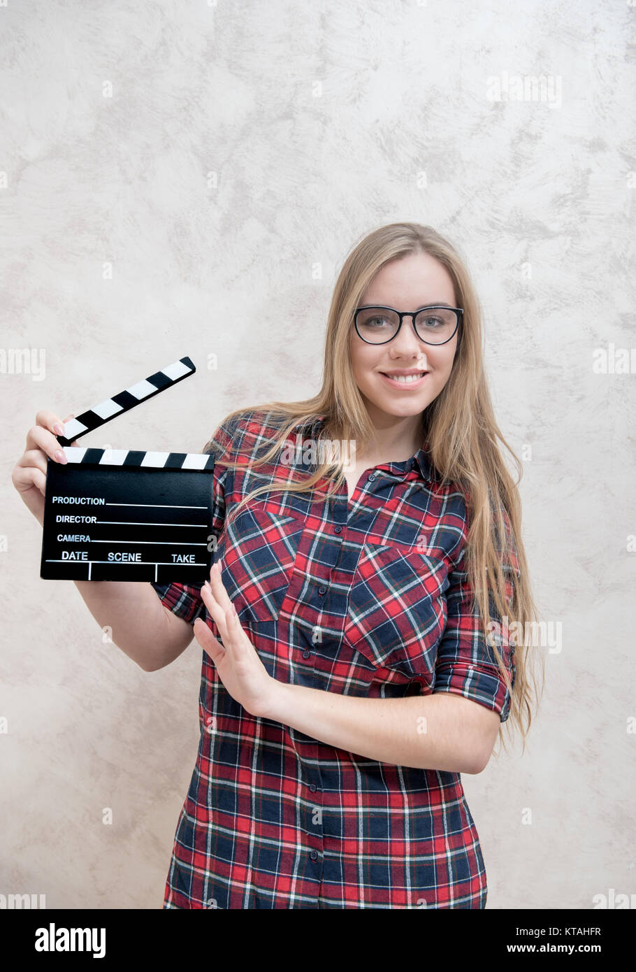 Young blonde woman actress posing with movie clapper board smiling and looking at camera Stock Photo