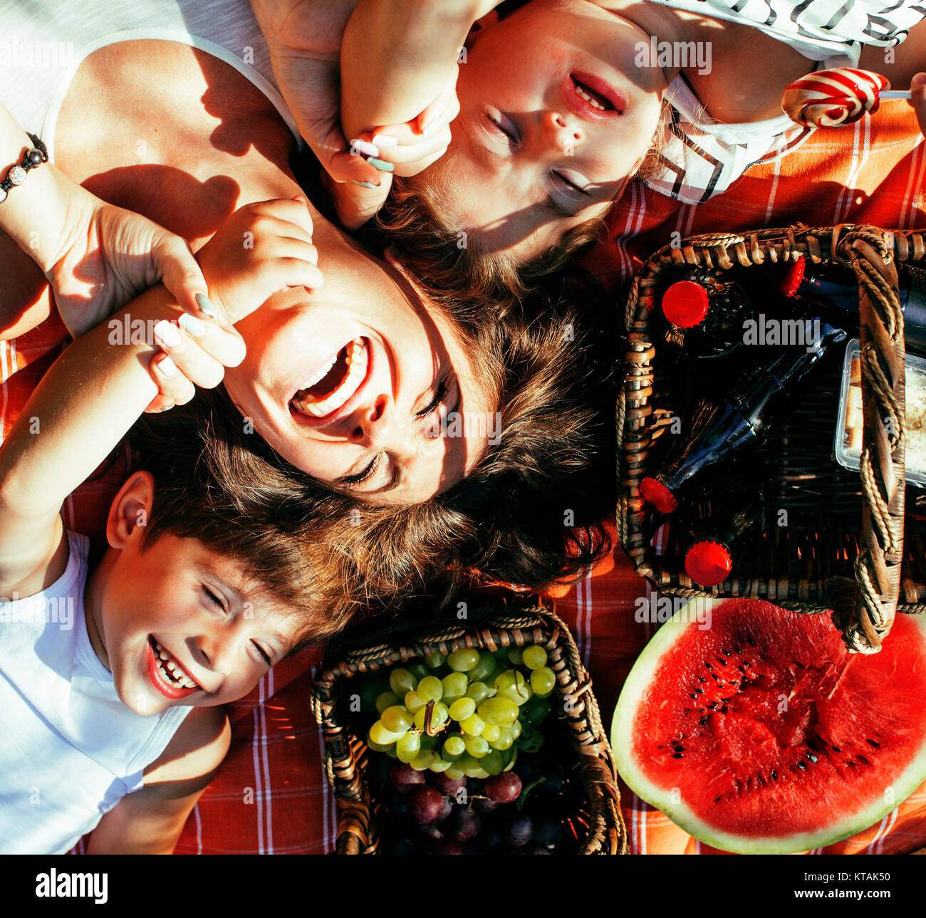 cute happy family on picnic laying on green grass mother and kids, warm summer vacations close up Stock Photo