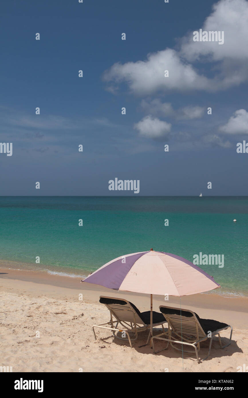 Beach umbrella and chaise lounges on seashore. St. George's, Grenada Stock Photo