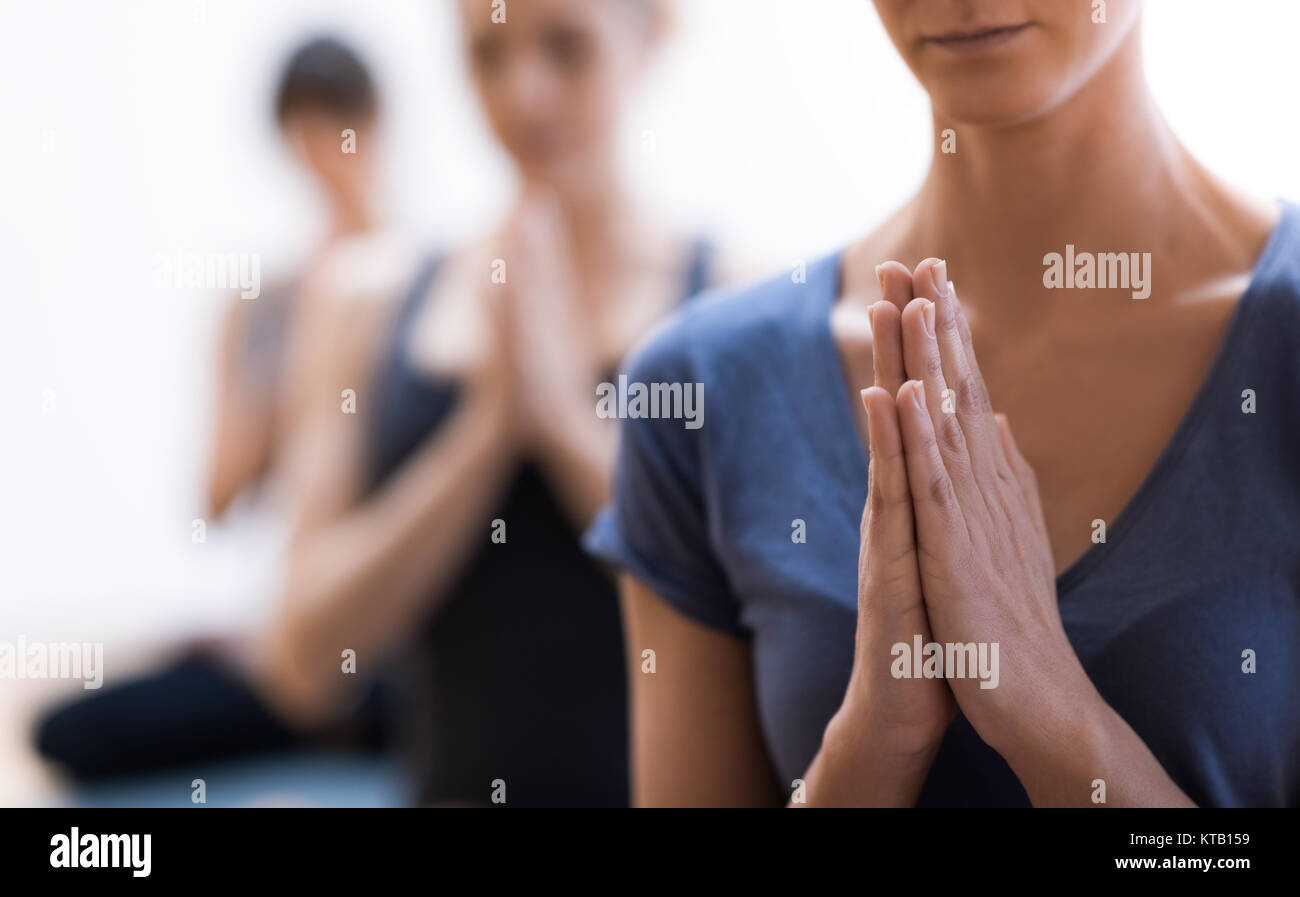 Women practicing yoga and mindfulness meditation together, they are clasping hands and relaxing, healthy lifestyle and spirituality concept Stock Photo