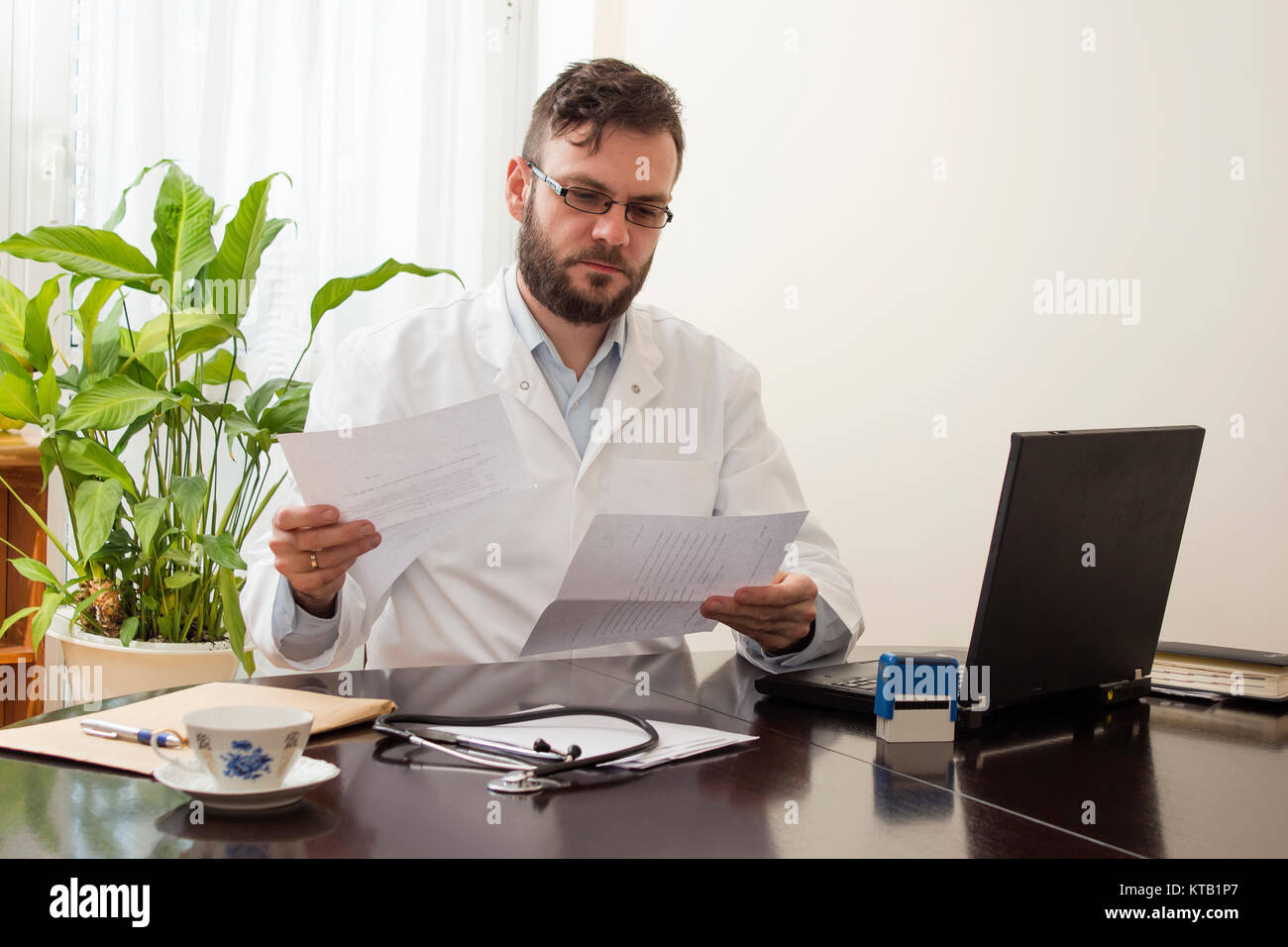 doctor in the office and reading medical records Stock Photo