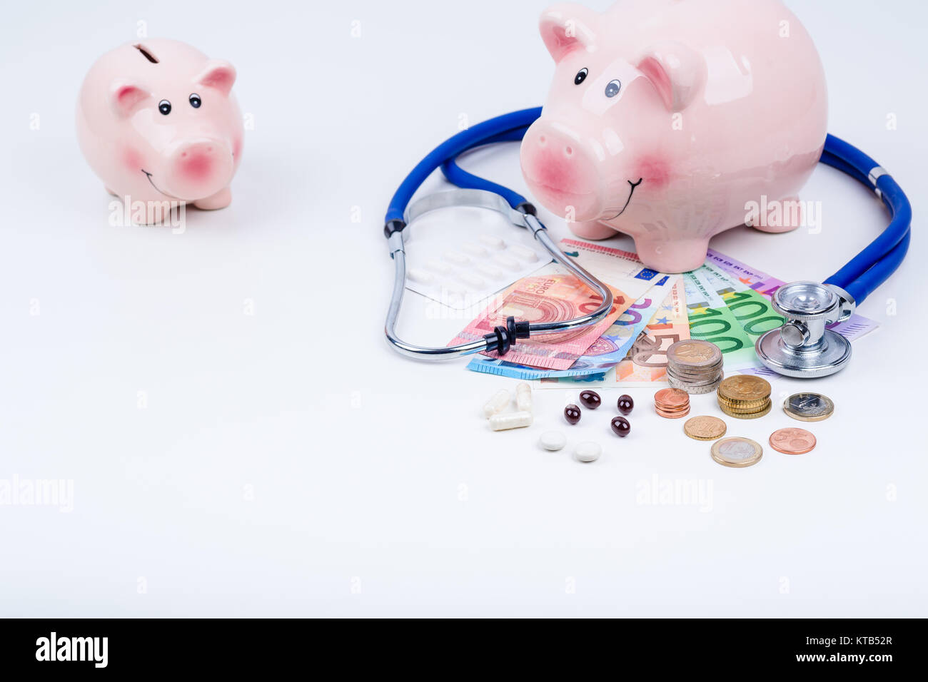 Kleines und Großes Sparschwein mit Geld,Münzen,Stethoskop und Medikamenten Stock Photo