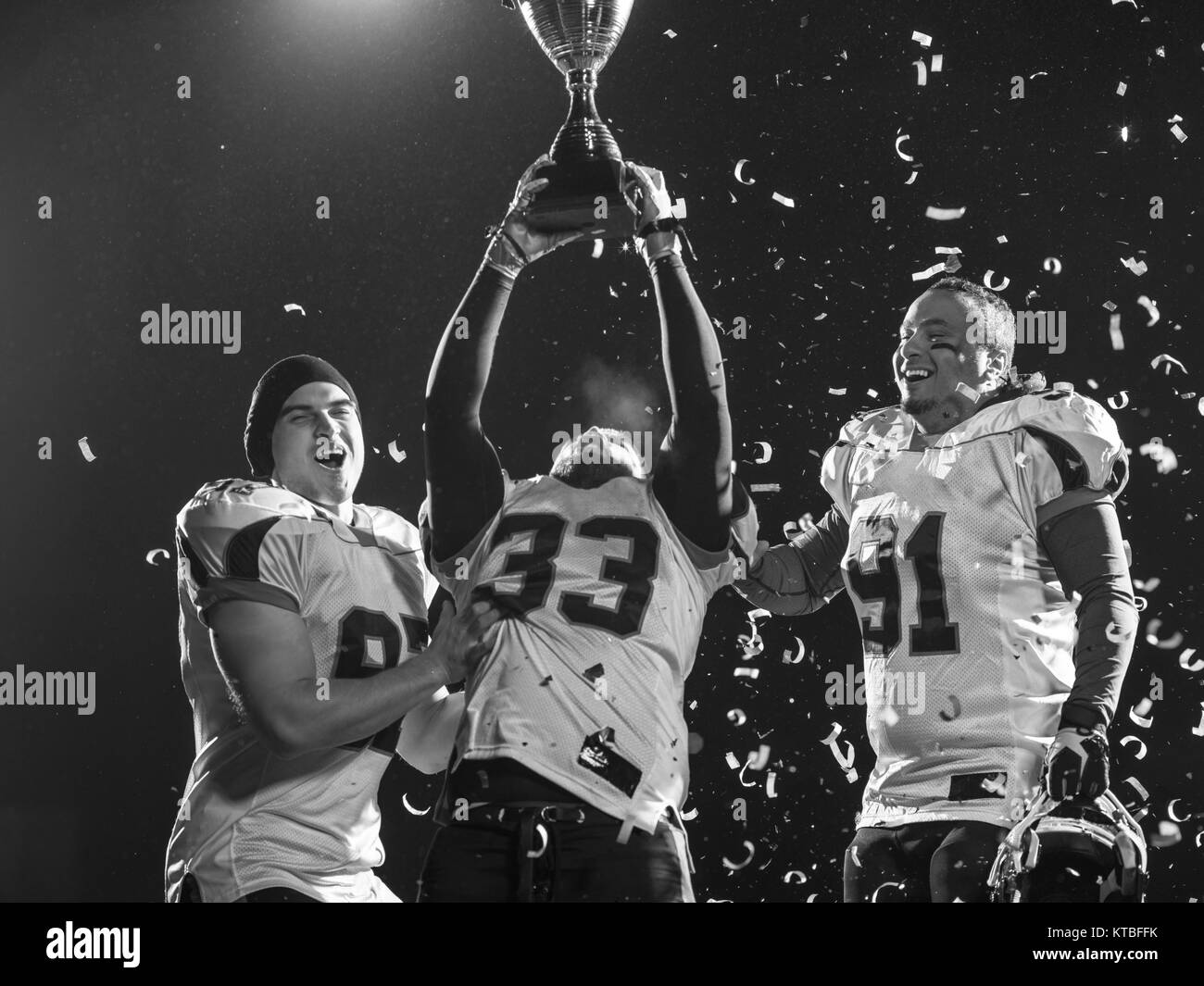 happy american football team celebrating victory with trophy and