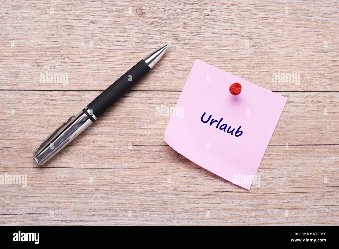 Wort Urlaub auf rosa Handzettel mit roter Nadel und Kugelschreiber Stock Photo