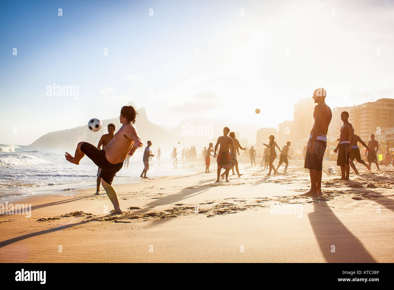 RIO DE JANEIRO, BRAZIL - APRIL 24, 2015: Carioca Brazilians playing altinho futebol beach football kicking soccer balls at sunset Ipanema Beach on Apr Stock Photo