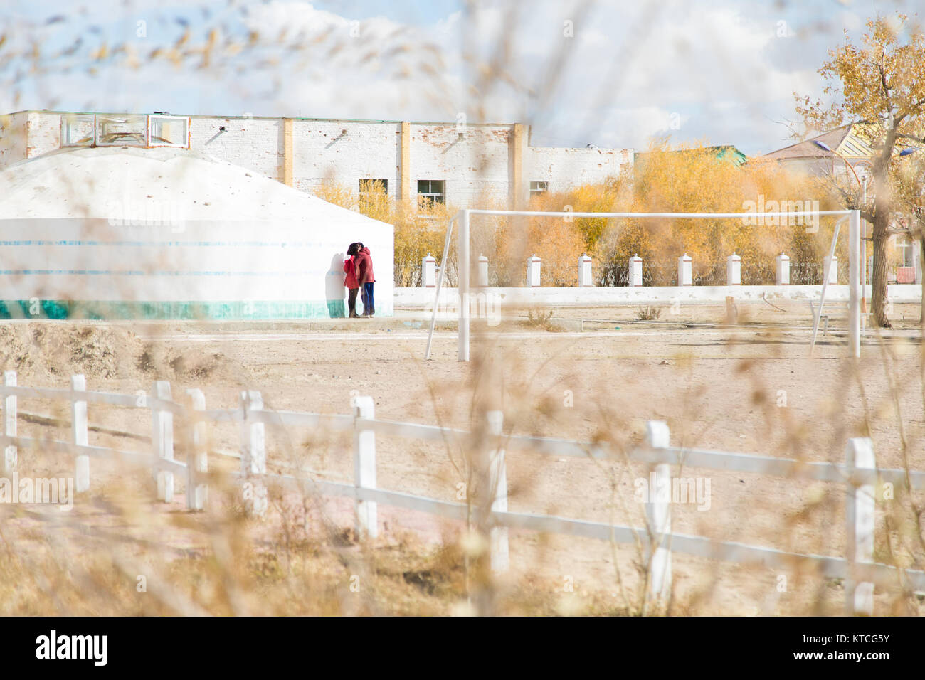A young couple in Mongolia steal a kiss framed by autumn leaves Stock Photo
