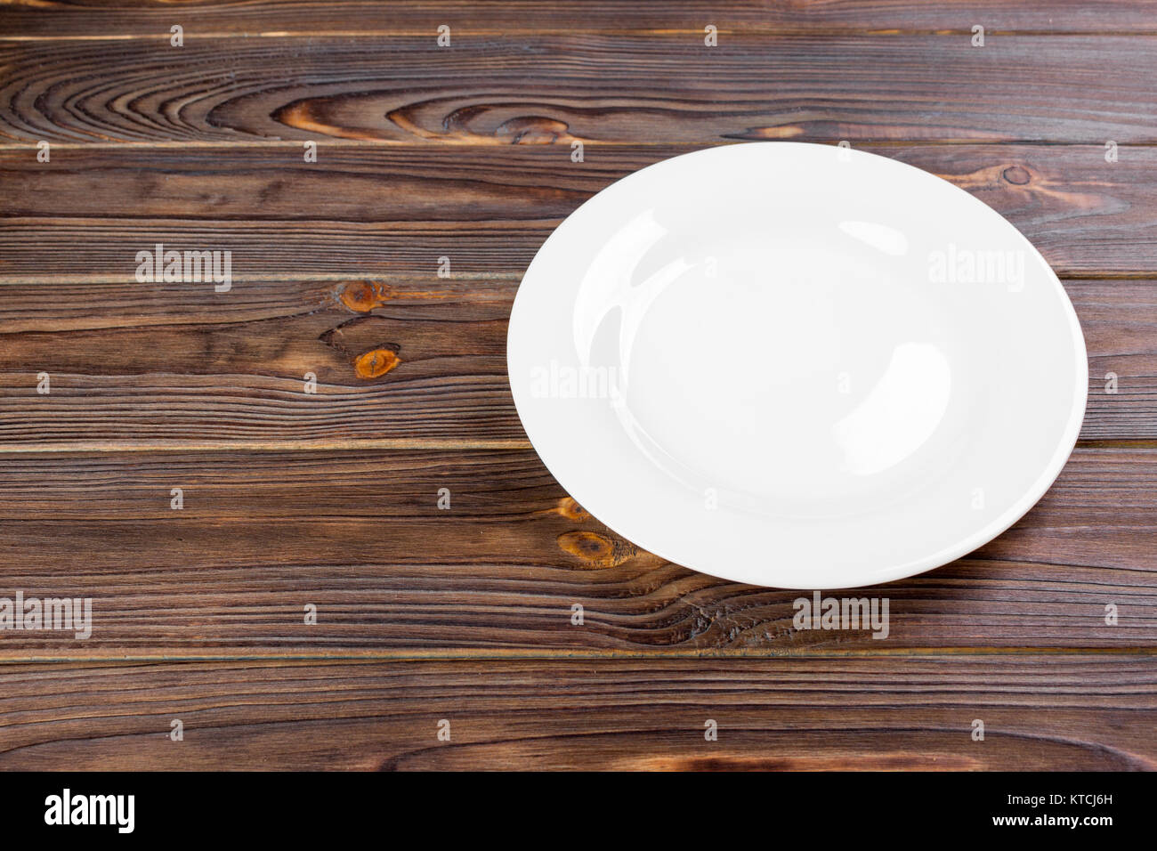 Empty white plate on wooden table top view Stock Photo - Alamy