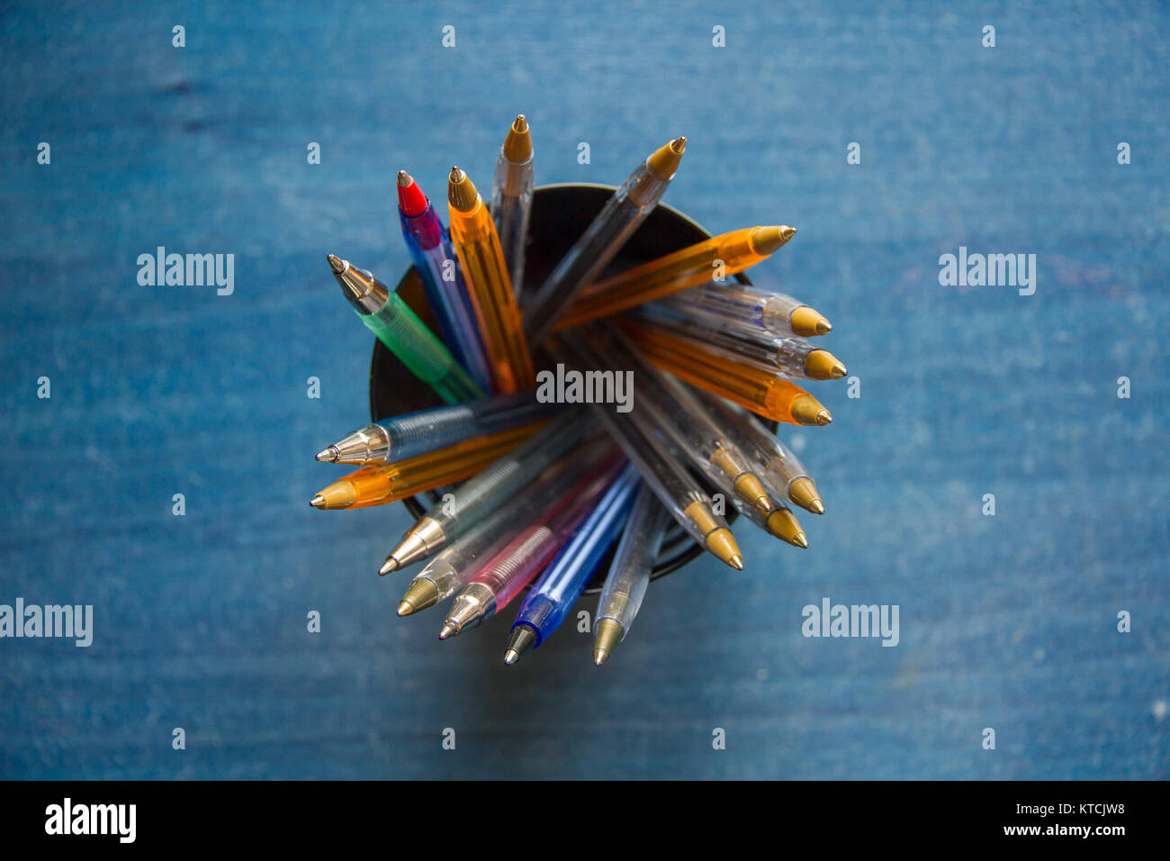 Pens of different colors in a case on top of a blue table Stock Photo ...