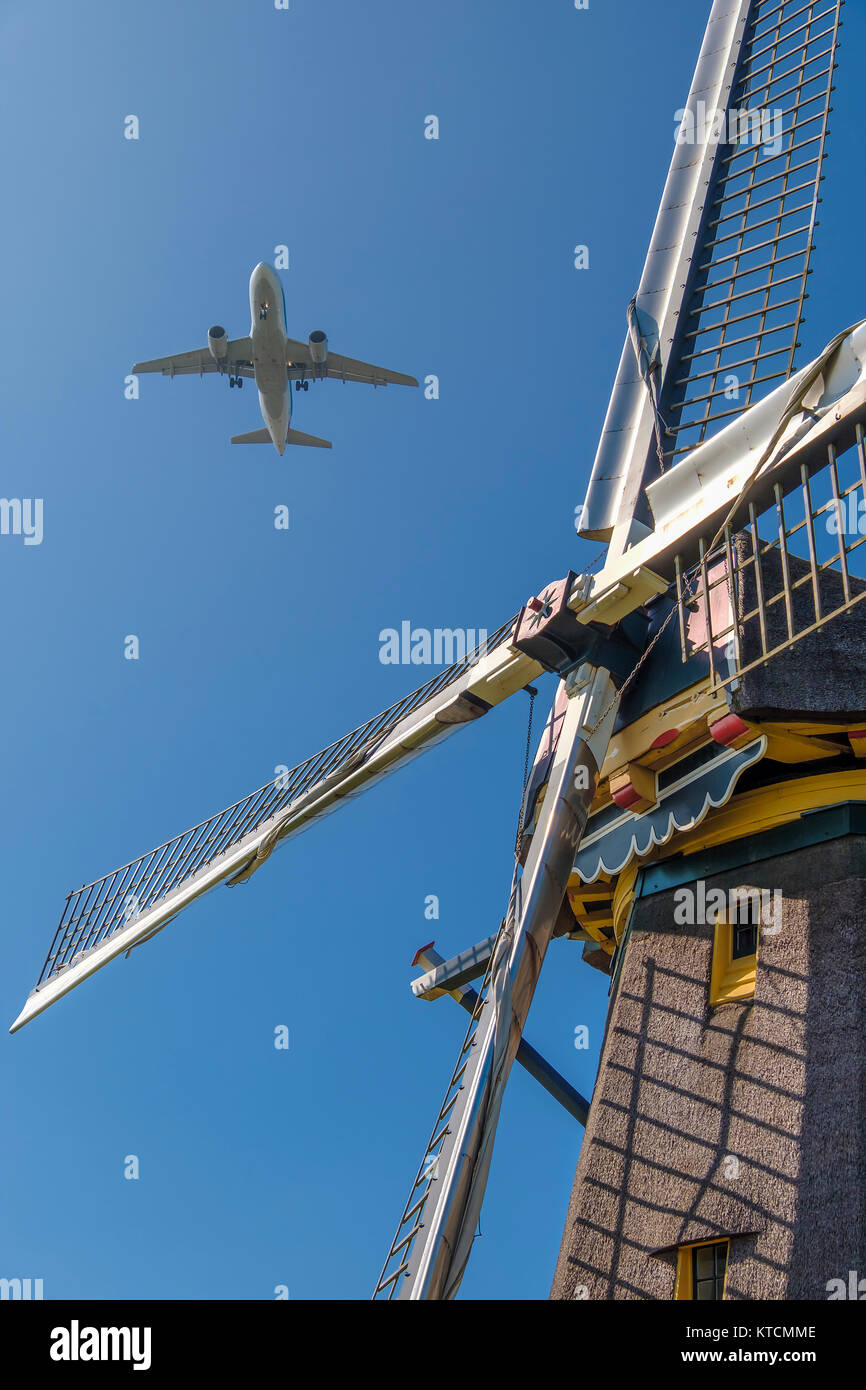 modern airplane flies past a traditional dutch windmill Stock Photo