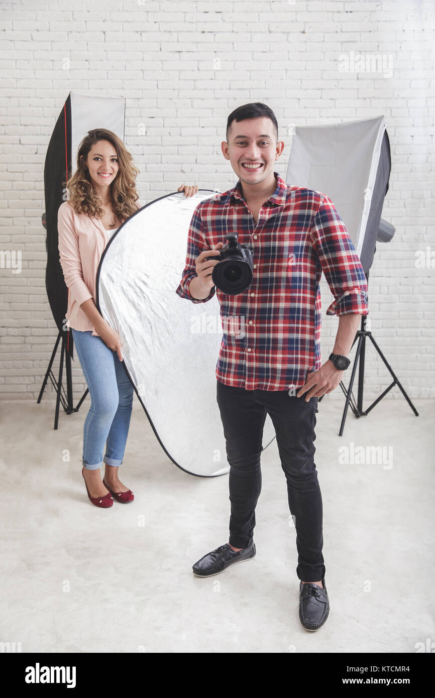 young photographer with his beautiful assistant in studio Stock Photo