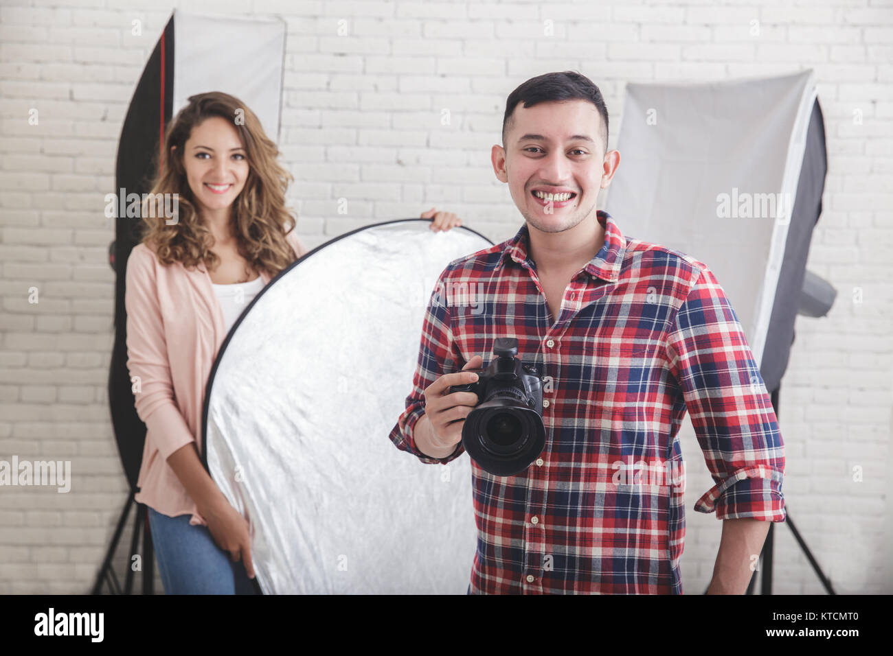 young photographer with his beautiful assistant in studio Stock Photo