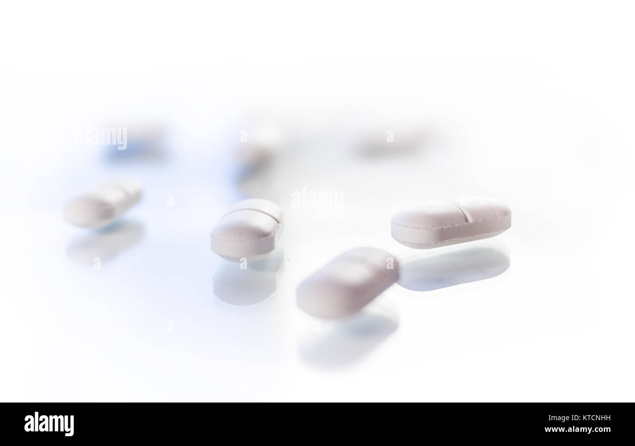 White tablets isolated on glass reflective surface Stock Photo
