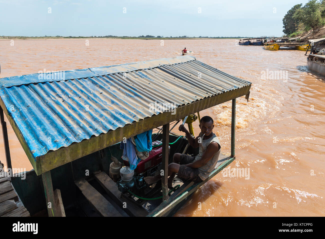 A Malagasy man running a makeshift motor boat on Mania River. Madagascar, Africa. Stock Photo