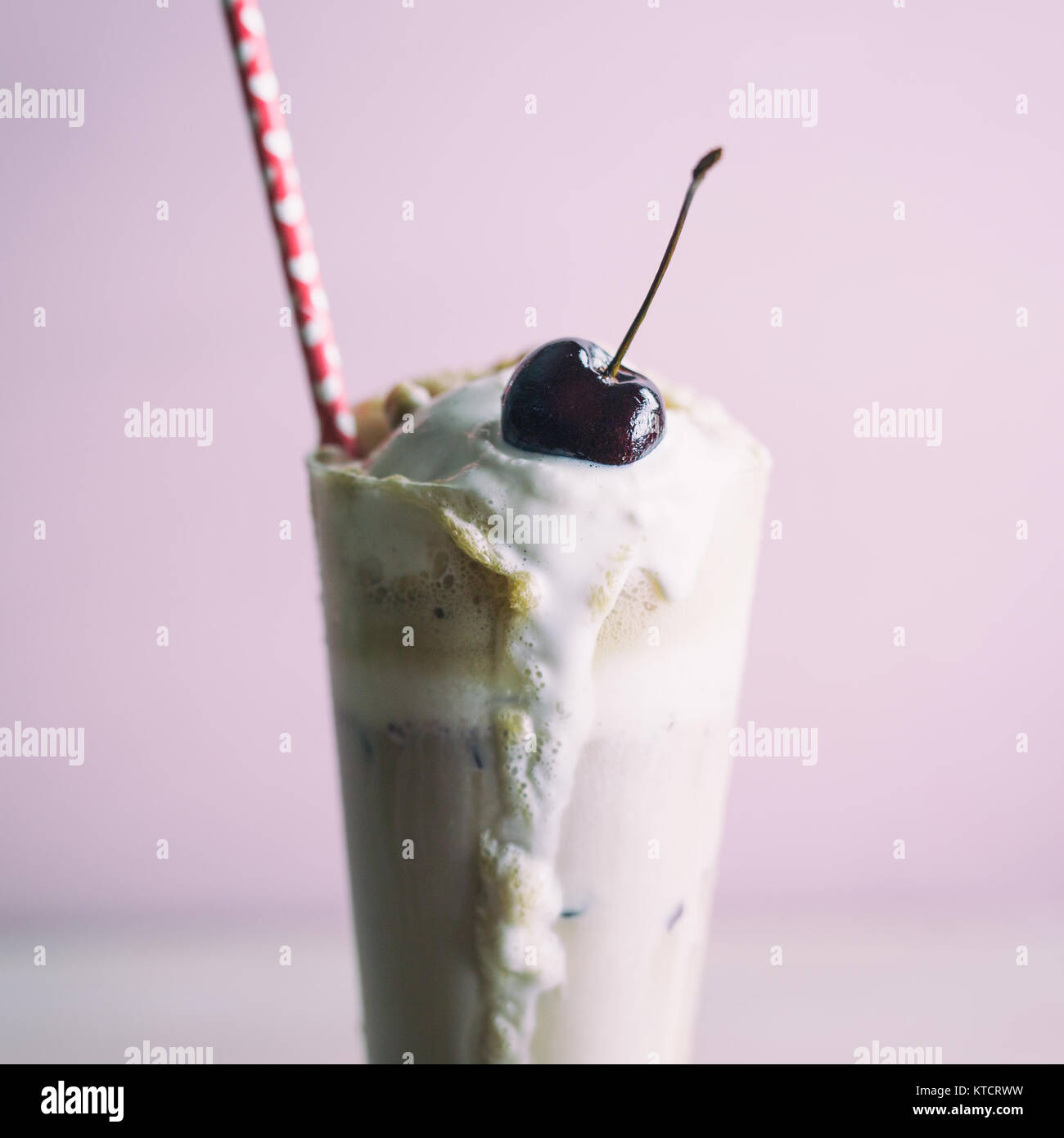 Tall root beer float with a fresh cherry on top and red straw with