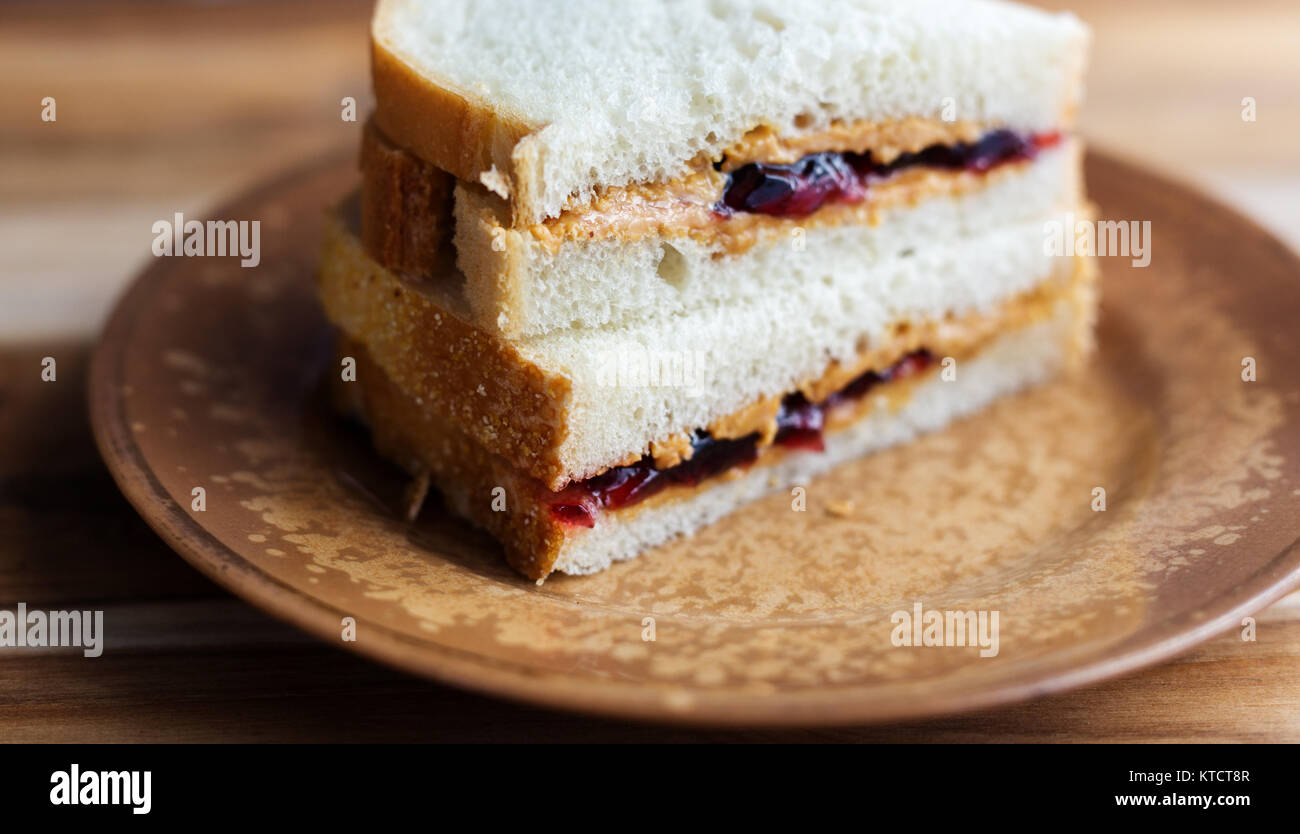 Peanut butter and jelly sandwich on white bread, cut in half and stacked. Shown on small vintage plate Stock Photo