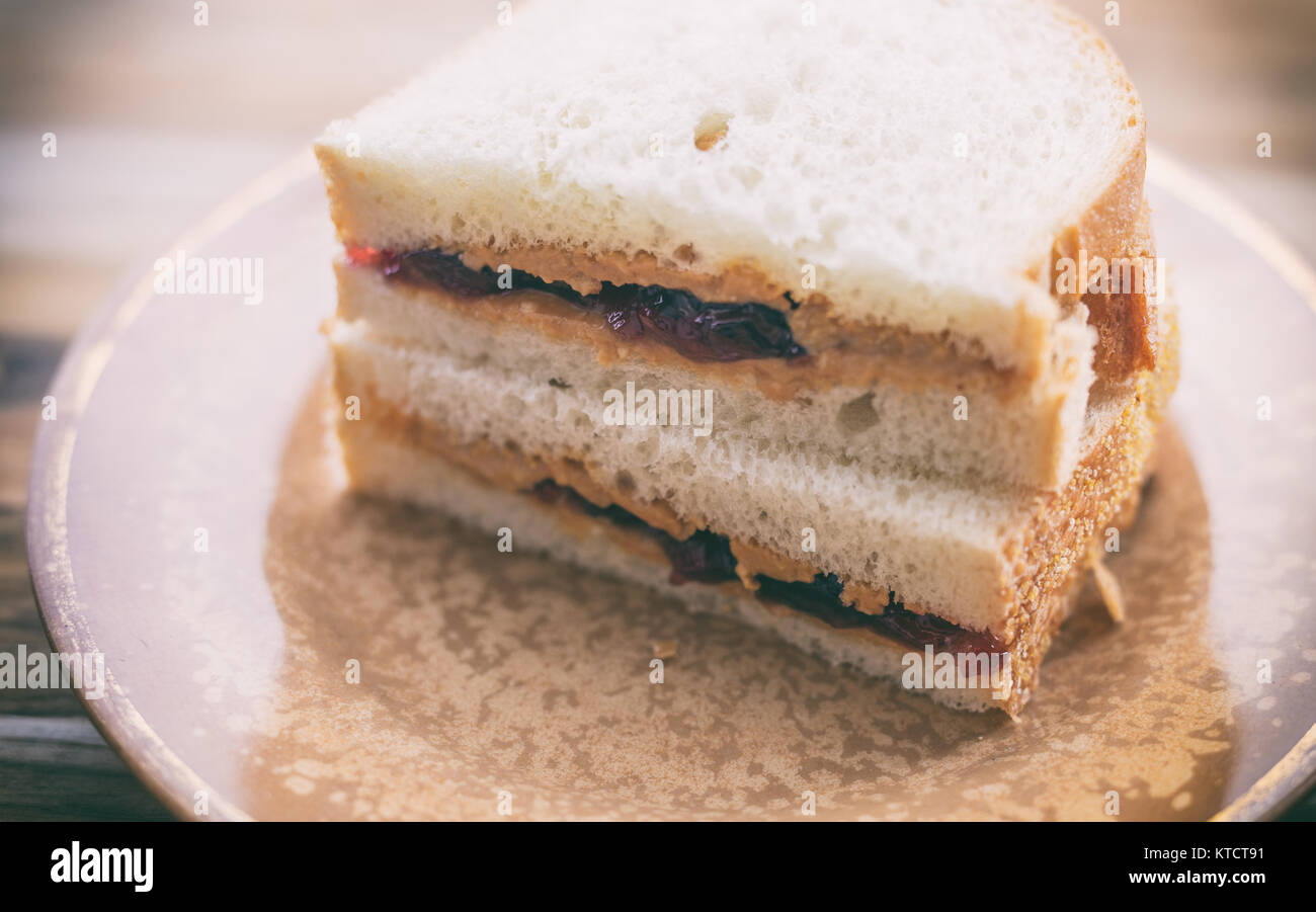 Peanut butter and jelly sandwich on white bread, cut in half and stacked. Shown on small vintage plate Stock Photo