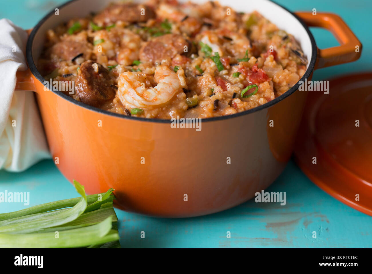 A cast iron pot filled with Jambalaya on a turquoise table Stock Photo