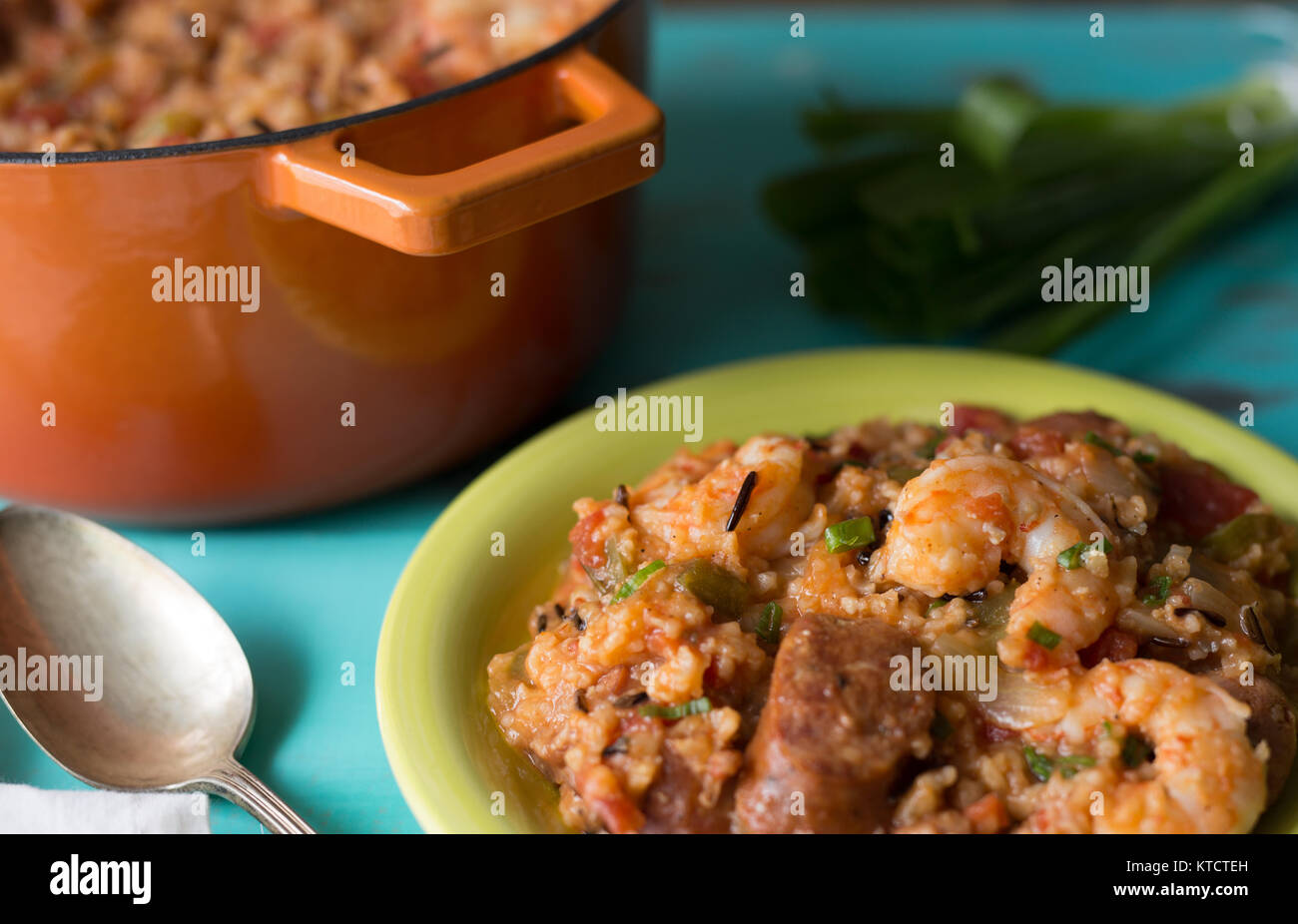 Jambalaya being served from a cast iron pot. Shown with antique serving