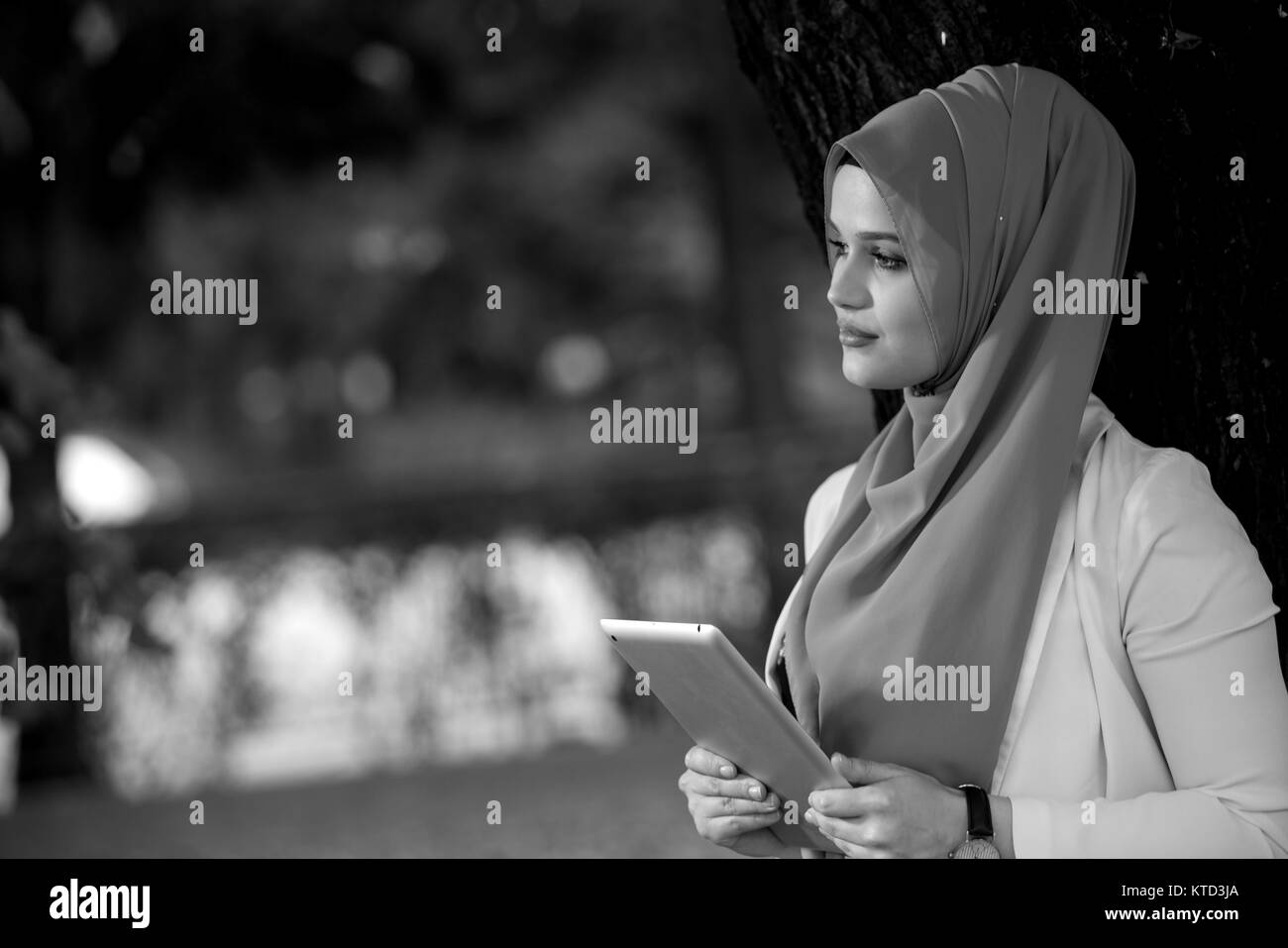 Young girl wearing hijab using talbet outside happy stock image