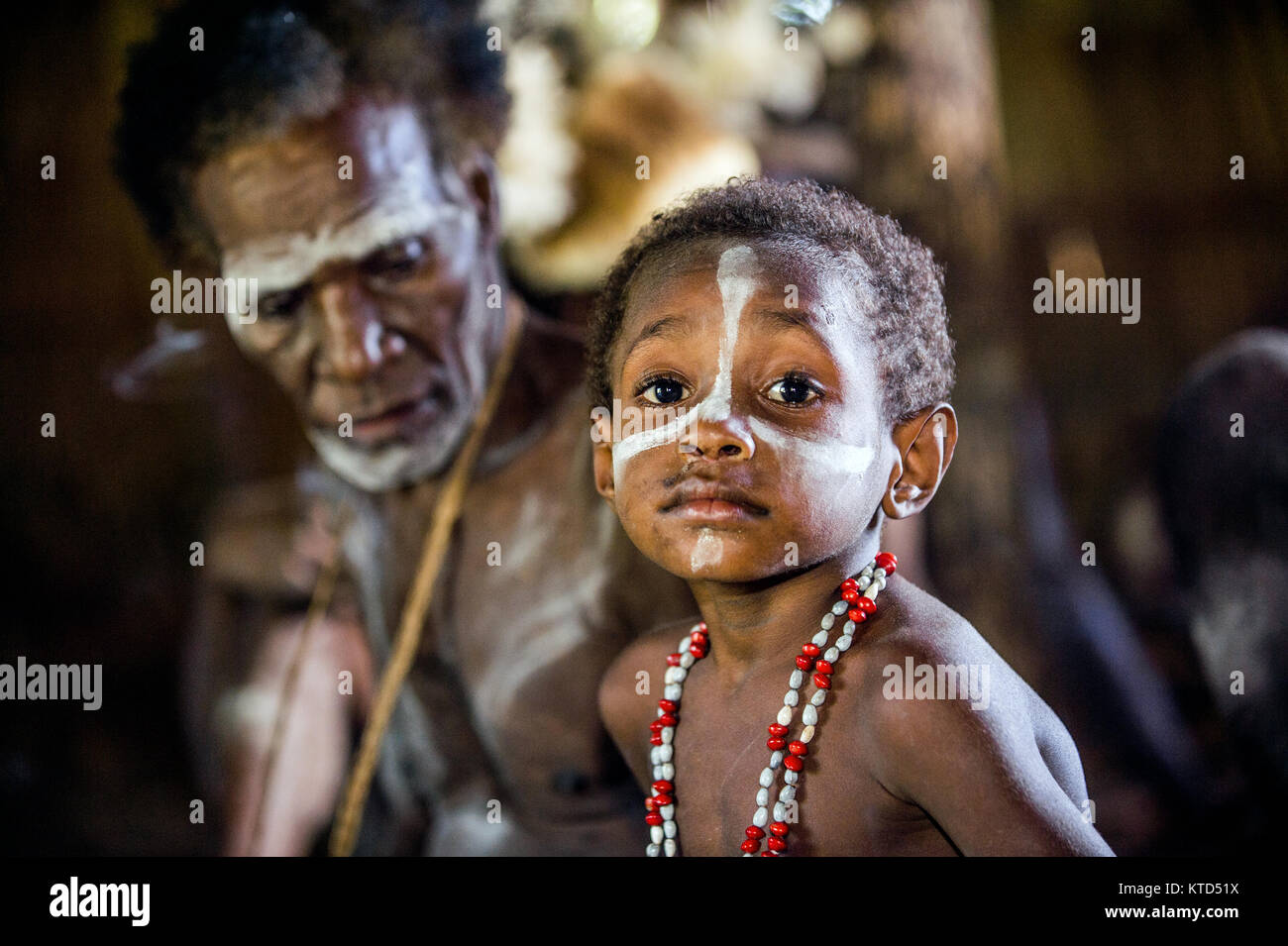 WEST PAPUA (IRIAN JAYA), ASMAT PROVINCE, NEW GUINEA, INDONESIA - MAY 22, 2016: - Unidentified boy of an asmat tribe painting face in a small forest vi Stock Photo