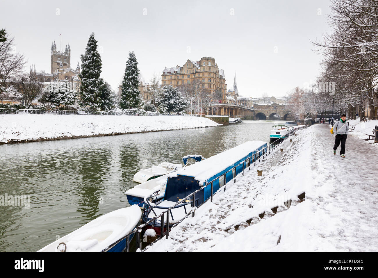 BATH, UK - 19 JANUARY, 2013:  Snow covered canal boats moored along the River Avon in Central Bath with Bath Abbey, Great Pulteney Bridge and the Empi Stock Photo